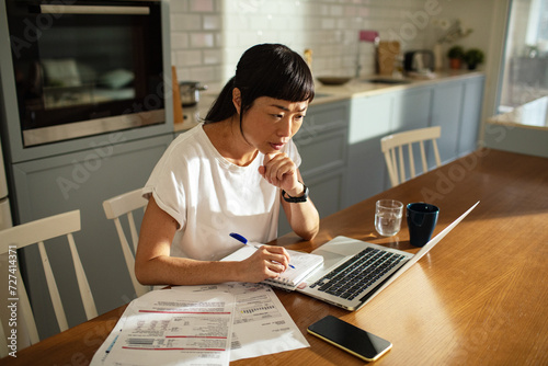 Young asian woman going over bills and home finances at home photo