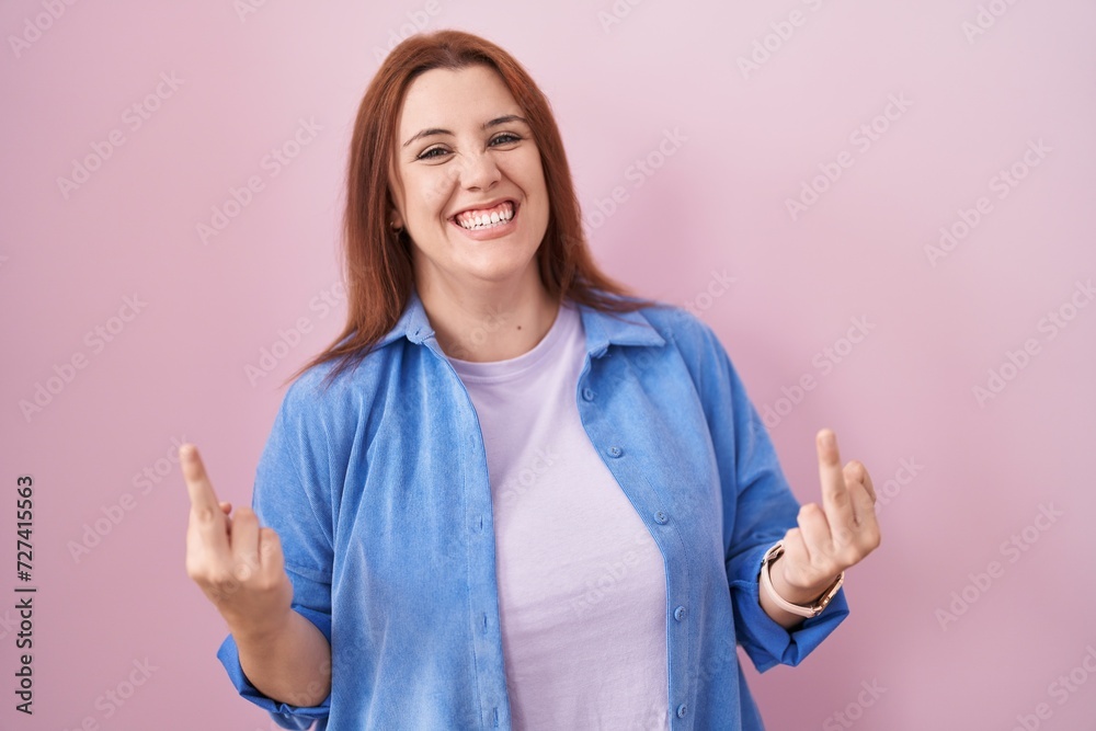 Young hispanic woman with red hair standing over pink background showing middle finger doing fuck you bad expression, provocation and rude attitude. screaming excited Young hispanic woman with red hair standing over pink background showing middle finger doing fuck you bad expression, provocation and rude attitude. screaming excited