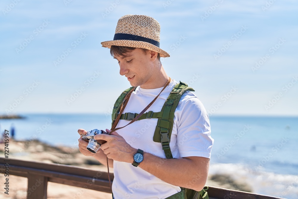 Young caucasian man tourist holding vintage camera at seaside