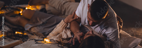 Banner. Romantic surprise for girlfriend or boyfriend on Saint Valentine's Day. Bedroom prepared for watching old movies, decorated with lights and burning candles. Cozy home Christmas atmosphere
