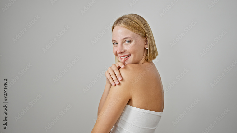 Obraz premium Young blonde woman smiling confident touching shoulder over isolated white background