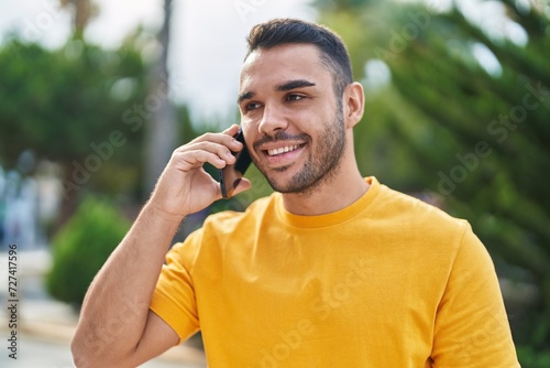 Young hispanic man smiling confident talking on the smartphone at park