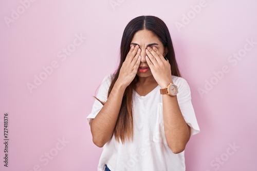 Young arab woman standing over pink background rubbing eyes for fatigue and headache, sleepy and tired expression. vision problem