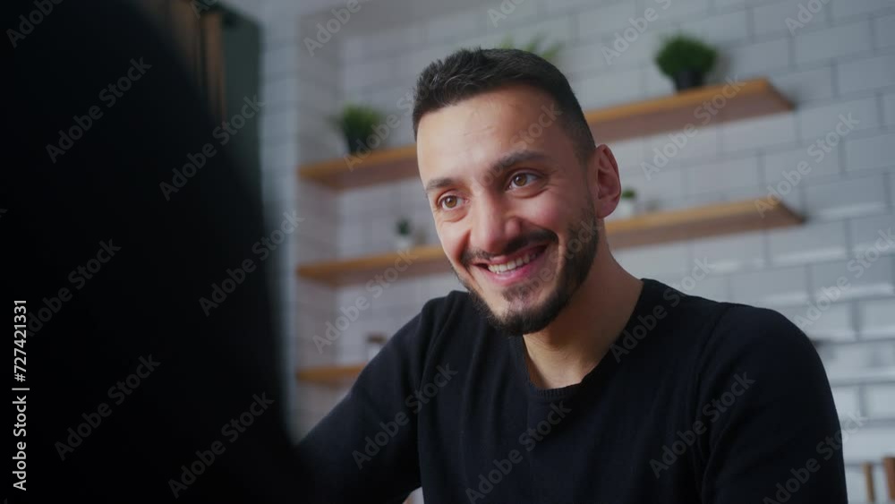 Smiling man chatting and having good time, friendly dispute debate with friend, laughing while sitting in the kitchen at home. OTS shot Smiling man chatting and having good time, friendly dispute debate with friend, laughing while sitting in the kitchen at home. OTS shot