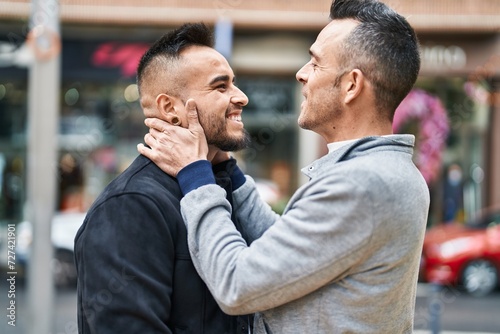 Two men couple smiling confident hugging each other at street