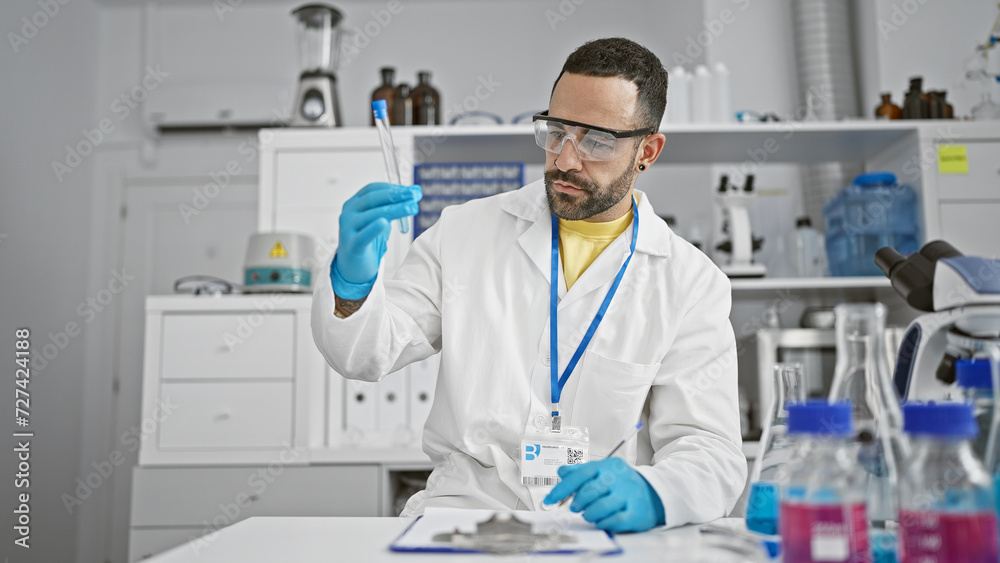 Hispanic man examines test tube in a laboratory setting, reflecting professionalism and expertise.