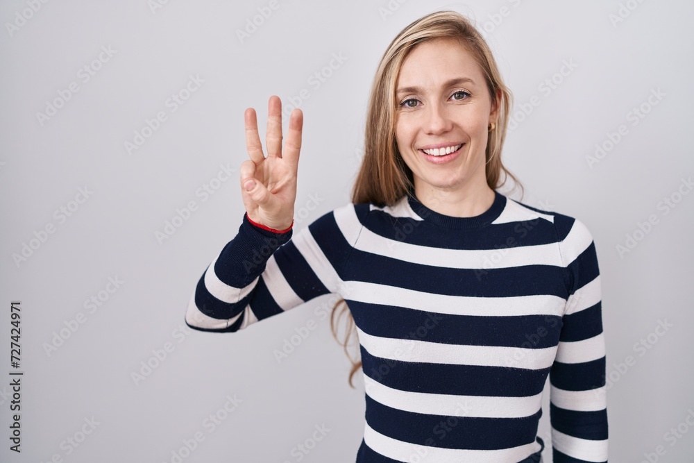 Young caucasian woman wearing casual navy sweater showing and pointing up with fingers number three while smiling confident and happy.
