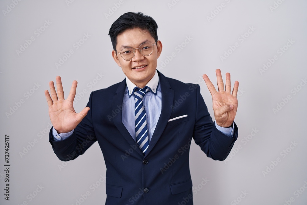 Young asian man wearing business suit and tie showing and pointing up with fingers number nine while smiling confident and happy. Young asian man wearing business suit and tie showing and pointing up with fingers number nine while smiling confident and happy.