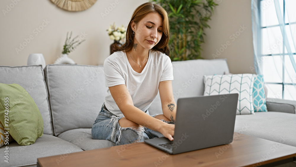 Young woman using laptop sitting on sofa at home Young woman using laptop sitting on sofa at home