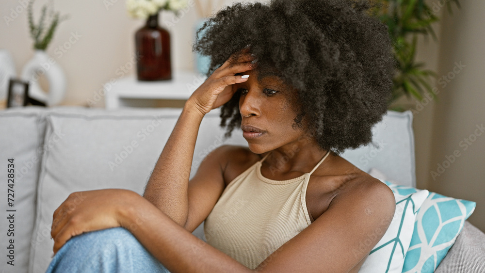 African american woman sitting on sofa with serious expression at home African american woman sitting on sofa with serious expression at home