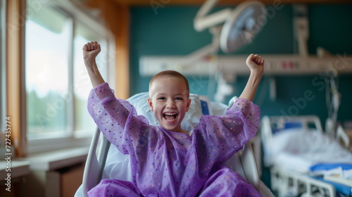 Happy child cancer patient in hospital bed raising hands. Joyful kid celebrating successful treatment. World cancer day, victory over disease, childhood cancer awareness, receiving good news.