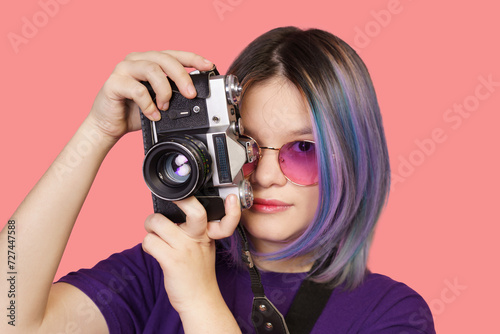 Teenager asian girl with old school photo camera against vibrant pink background. Youthful enthusiasm for photography, combining modern era with vintage charm of analog camera. close-up portrait. High photo