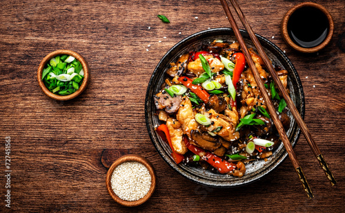 Stir fry turkey slices with red paprika, mushrooms, chives and sesame seeds with ginger, garlic and soy sauce. Old wooden table background, top view