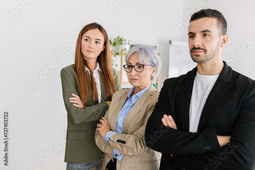 Successful three business people with crossed arms standing together as a successful team at office.