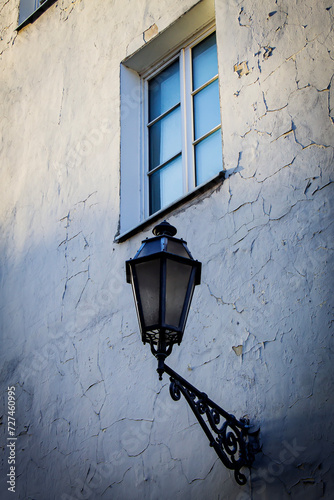 A street lamp on the wall of a house in the old center of Vilnius. A lamp and a window