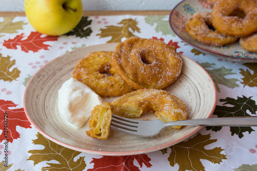 Buñuelos de manzana sobre mantel otoñal con hojas. Postre frito de manzana