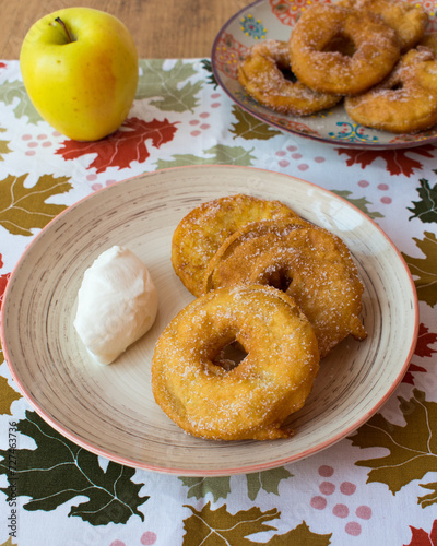 Buñuelos de manzana sobre mantel otoñal con hojas. Postre frito de manzana