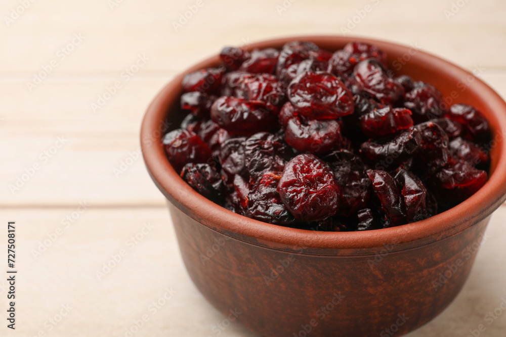 Tasty dried cranberries in bowl on light wooden table, closeup Tasty dried cranberries in bowl on light wooden table, closeup