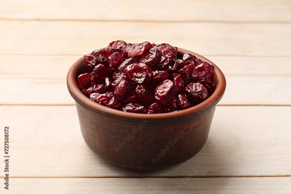 Tasty dried cranberries in bowl on light wooden table, closeup Tasty dried cranberries in bowl on light wooden table, closeup