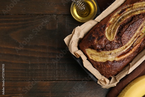 Delicious banana bread and honey on wooden table, top view. Space for text