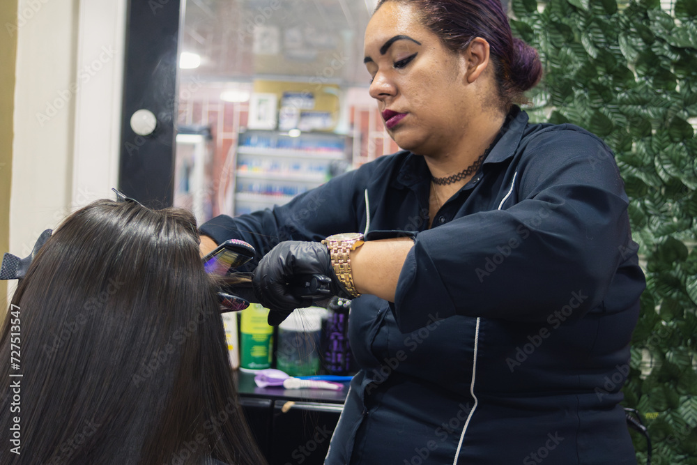 a woman straightening the hair of another Latin woman a woman straightening the hair of another Latin woman