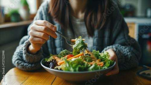 Woman eating fresh salad in the kitchen, close-up. Healthy food concept