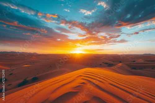As the sun dips below the horizon  its warm glow bathes the desert dunes in a spectacular display of orange and red hues  contrasting with the cool blue sky.