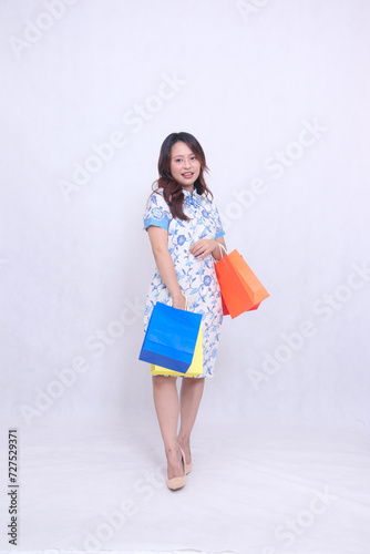 full body Beautiful Asian woman thin smile wearing modern chinese dress carrying many paper bags waist area isolated on white background. happy Chinese New Year