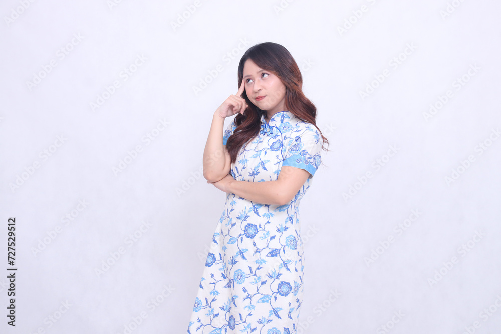 Beautiful indonesian woman thinking wearing modern chinese dress isolated on white background. happy Chinese New Year Beautiful indonesian woman thinking wearing modern chinese dress isolated on white background. happy Chinese New Year