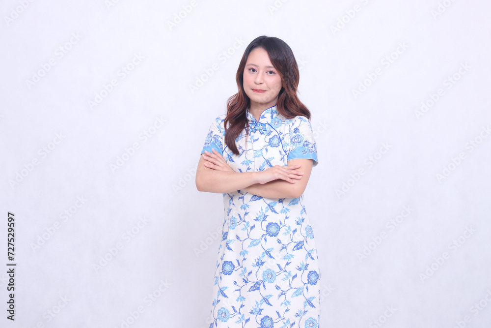 Beautiful Indonesian woman with graceful smile wearing modern Chinese dress with arms crossed isolated on white background. happy Chinese New Year Beautiful Indonesian woman with graceful smile wearing modern Chinese dress with arms crossed isolated on white background. happy Chinese New Year
