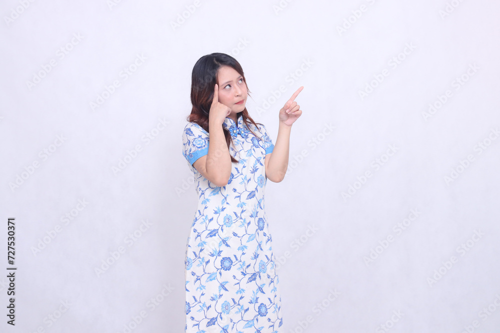 beautiful Javanese Chinese woman thinking wearing a modern Chinese dress showing her brain and hand pointing up left on a white background. happy Chinese New Year beautiful Javanese Chinese woman thinking wearing a modern Chinese dress showing her brain and hand pointing up left on a white background. happy Chinese New Year