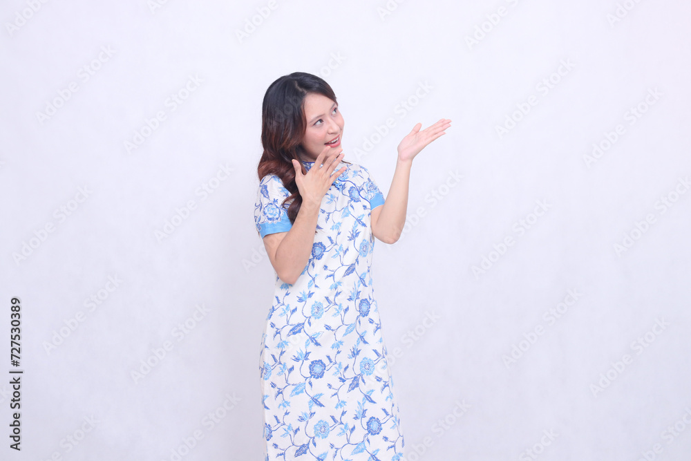 Beautiful cheerful Javanese Chinese woman wearing modern Chinese dress view top left and hand presenting isolated white background. happy Chinese New Year Beautiful cheerful Javanese Chinese woman wearing modern Chinese dress view top left and hand presenting isolated white background. happy Chinese New Year