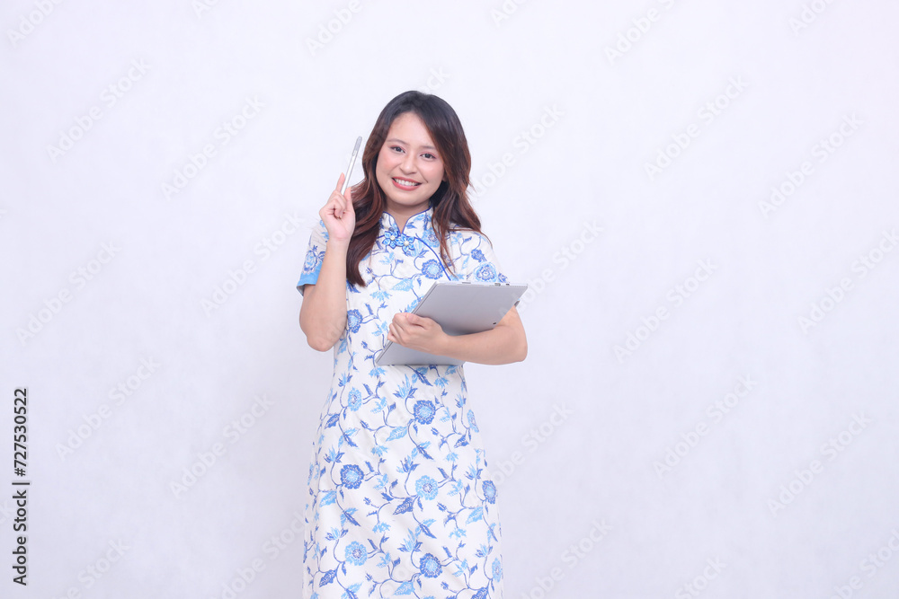 Beautiful Chinese Indonesian woman smile wearing modern Chinese blue dress carrying tablet and pen pose can idea isolated white background Beautiful Chinese Indonesian woman smile wearing modern Chinese blue dress carrying tablet and pen pose can idea isolated white background