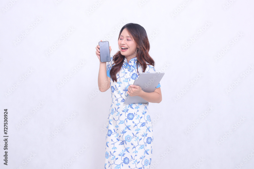 beautiful asian woman wearing blue chinese dress looking at cellphone happily holding tablet and looking at cellphone screen isolated white background beautiful asian woman wearing blue chinese dress looking at cellphone happily holding tablet and looking at cellphone screen isolated white background