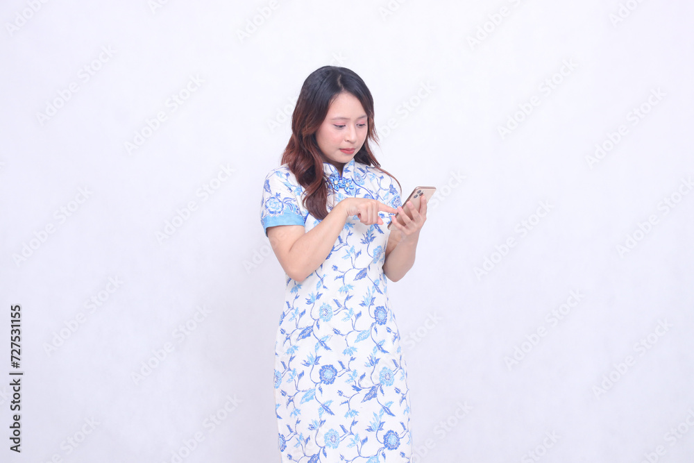 young asian javanese chinese woman wearing left sided chinese blue dress while operating gadget forefinger pressing cell phone isolated white background young asian javanese chinese woman wearing left sided chinese blue dress while operating gadget forefinger pressing cell phone isolated white background