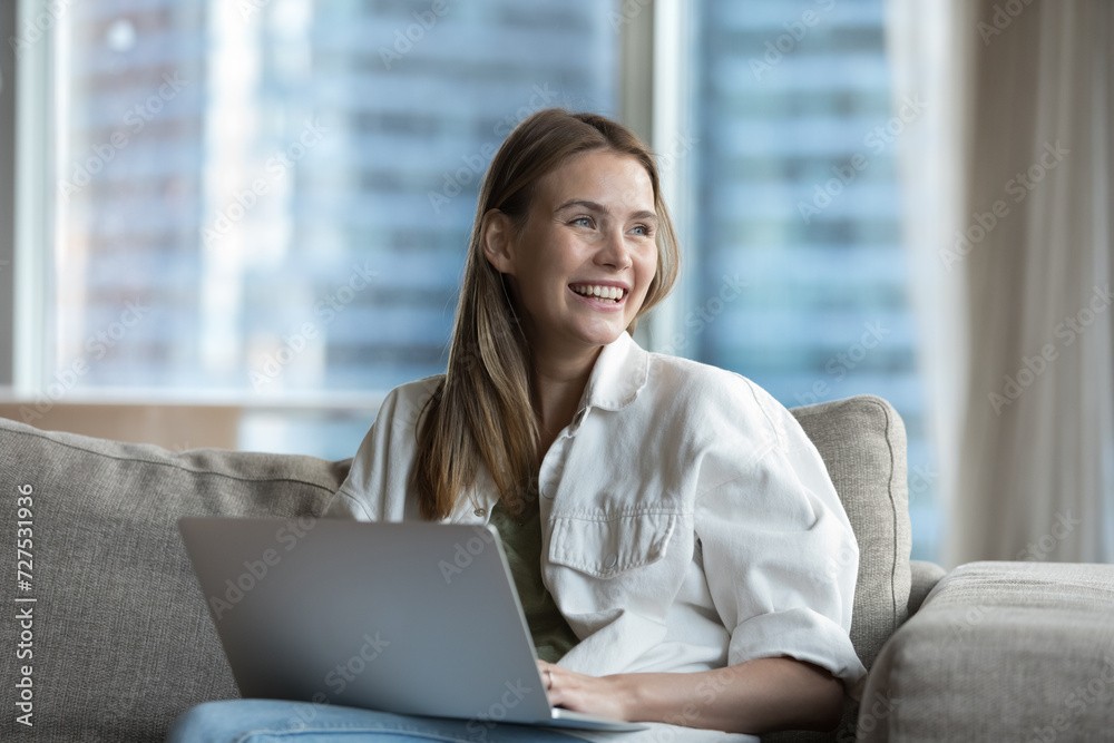 Beautiful happy young woman spend time on internet sit on sofa with laptop, enjoy pleasant chat with boyfriend in social media, receive good news in e-mail, having pleasant communication by messaging Beautiful happy young woman spend time on internet sit on sofa with laptop, enjoy pleasant chat with boyfriend in social media, receive good news in e-mail, having pleasant communication by messaging