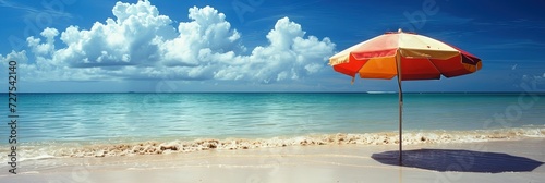 Colorful umbrella on empty sandy beach with the ocean and cloudy blue skies
