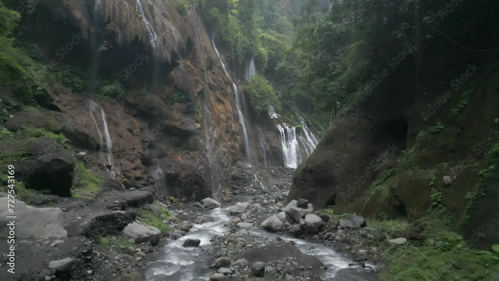 Aerial flies down narrow river canyon with waterfalls on cliff walls Aerial flies down narrow river canyon with waterfalls on cliff walls