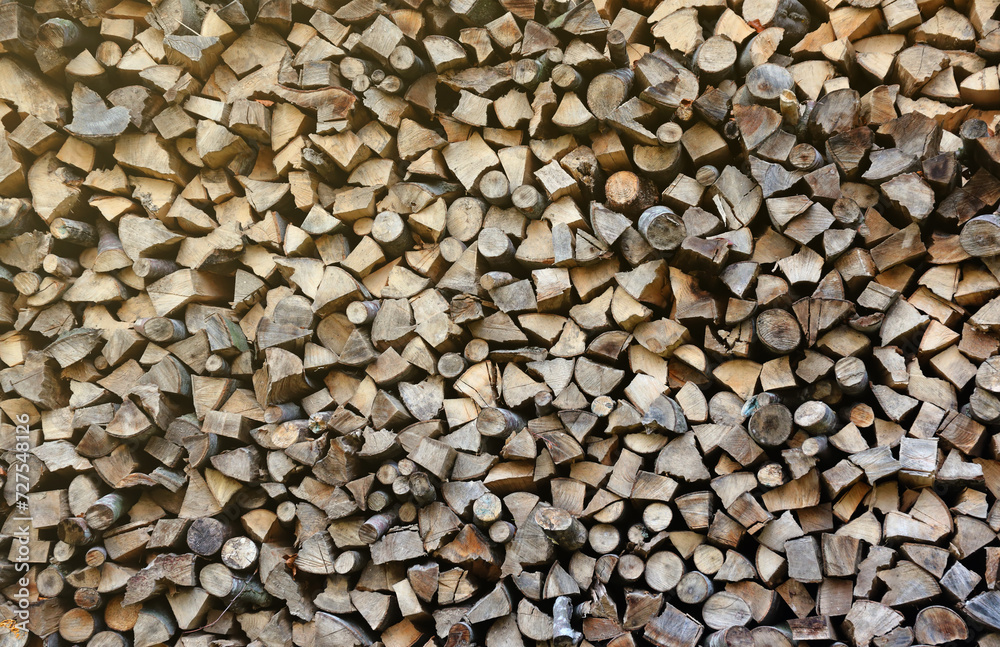 Firewood stacked near the wooden wall of old hut. Many chopped logs of firewood close up Firewood stacked near the wooden wall of old hut. Many chopped logs of firewood close up