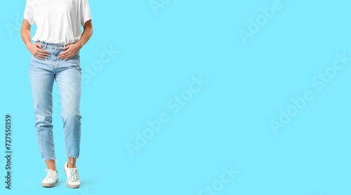 Stylish young woman in jeans on light blue background with space for text