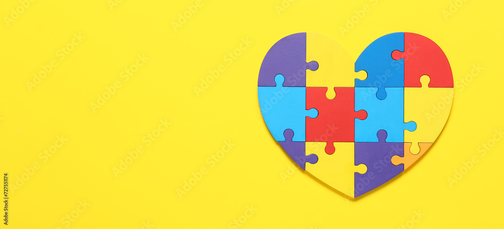 Obraz premium Heart made of colorful puzzle pieces on yellow background. Concept of autism spectrum disorder