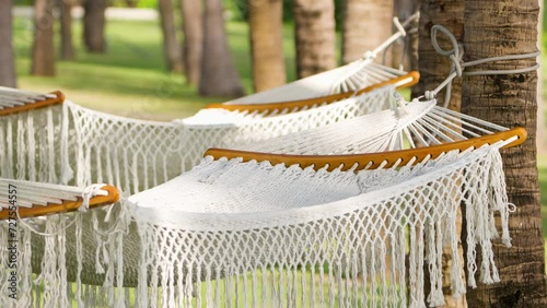 Two Empty White Rope Hammocks Swinging In Slow Motiong at Palm Tree Park in Vietnam photo