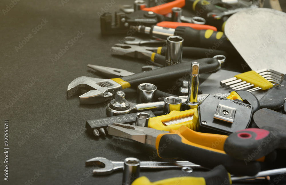 Fototapeta premium Handyman tool kit on black wooden table. Many wrenches and screwdrivers, pilers and other tools for any types of repair or construction works. Repairman tools set