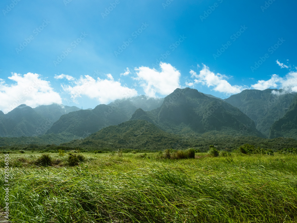 Rural countryside scenery, mountains, and blue sky with white clouds.	