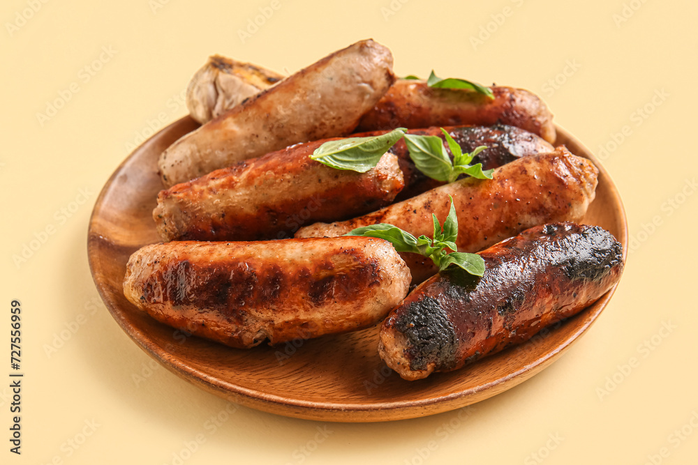 Plate of tasty grilled sausages on yellow background Plate of tasty grilled sausages on yellow background