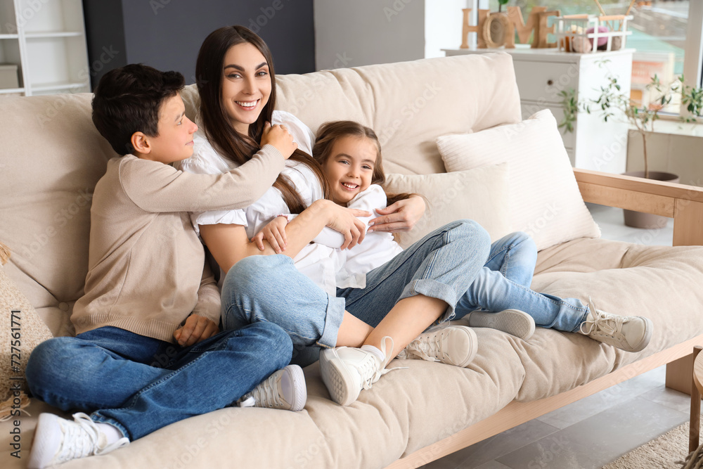 Young woman with her little children hugging on sofa at home. Mother's Day celebration Young woman with her little children hugging on sofa at home. Mother's Day celebration