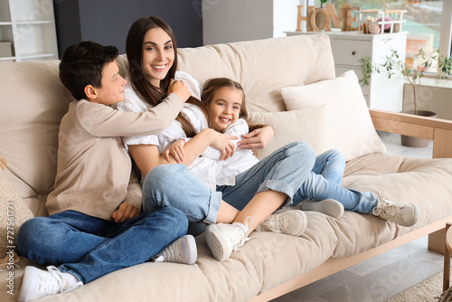 Young woman with her little children hugging on sofa at home. Mother's Day celebration