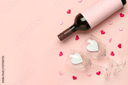 Composition with bottle of wine and glasses for Valentine's day on pink background