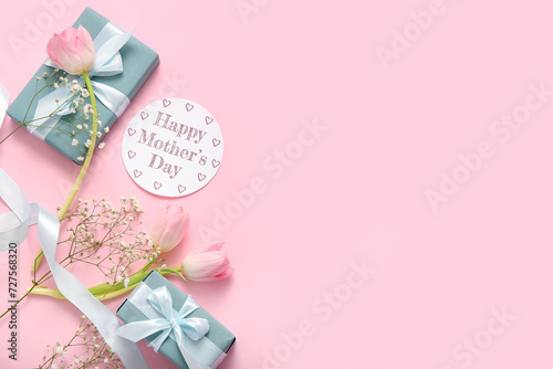Card with text HAPPY MOTHER'S DAY, gift boxes and beautiful flowers on pink background © Pixel-Shot