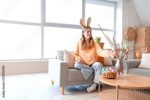 Canvas Print Young woman in bunny ears with willow branches and Easter eggs at home